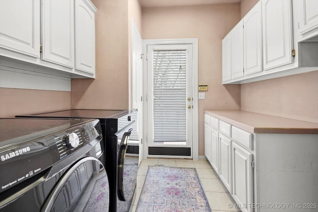 washroom with cabinets, washing machine and dryer, and light tile patterned floors