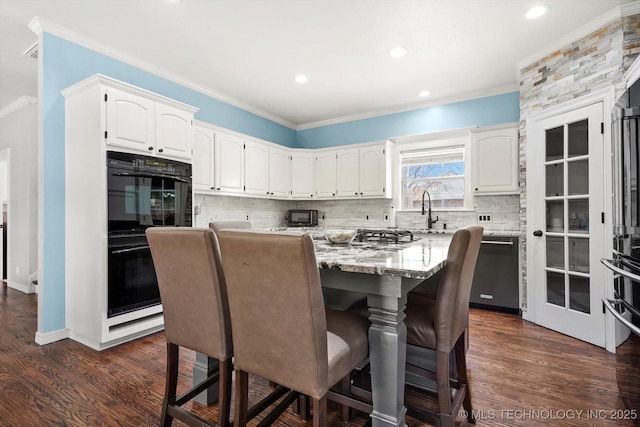 kitchen with white cabinetry, double oven, stainless steel dishwasher, and a kitchen island