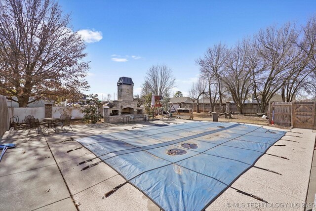 view of pool with a patio area and an outdoor stone fireplace