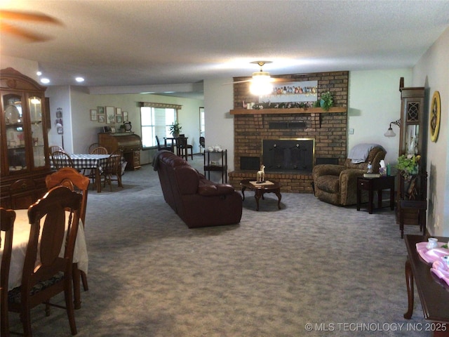 living room with dark colored carpet, a brick fireplace, and a textured ceiling