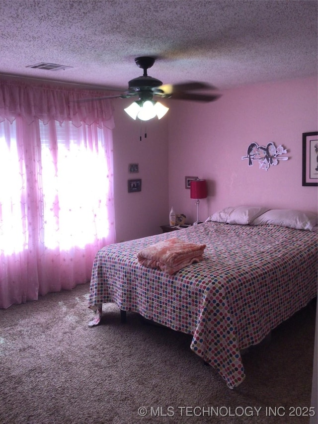 carpeted bedroom featuring ceiling fan and a textured ceiling