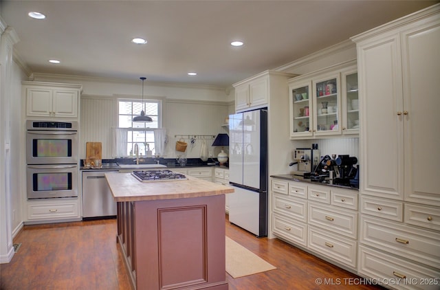 kitchen featuring wood counters, appliances with stainless steel finishes, dark hardwood / wood-style floors, ornamental molding, and a kitchen island