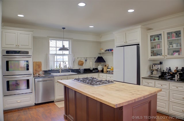 kitchen featuring wood counters, crown molding, appliances with stainless steel finishes, pendant lighting, and white cabinets