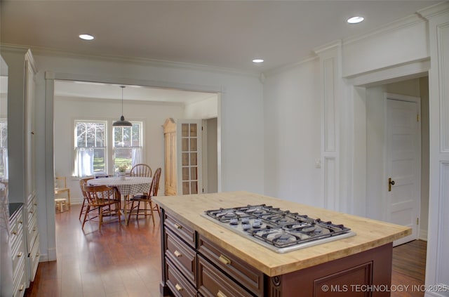 kitchen with crown molding, butcher block counters, a kitchen island, decorative light fixtures, and stainless steel gas stovetop