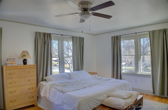 bedroom featuring multiple windows, ceiling fan, and light wood-type flooring