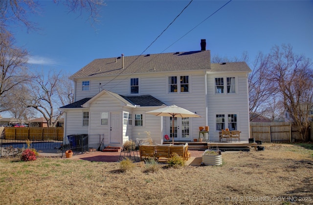 rear view of property with french doors, a patio, a wooden deck, and a lawn