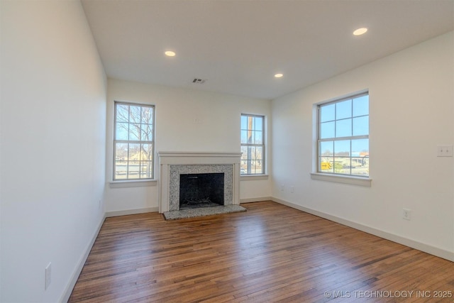 unfurnished living room with hardwood / wood-style flooring, a wealth of natural light, and a premium fireplace