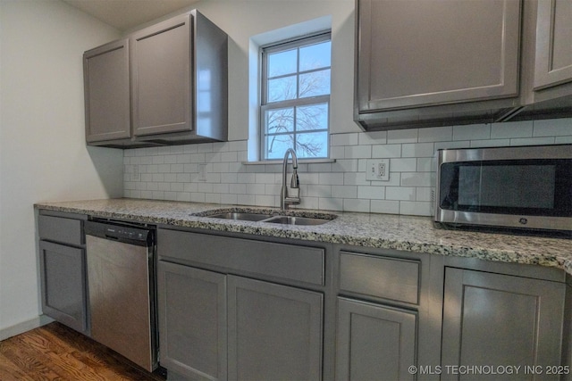 kitchen featuring sink, gray cabinetry, appliances with stainless steel finishes, light stone countertops, and backsplash