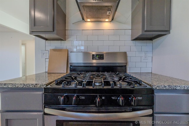 kitchen featuring gray cabinets, premium range hood, stainless steel range with gas stovetop, and light stone counters