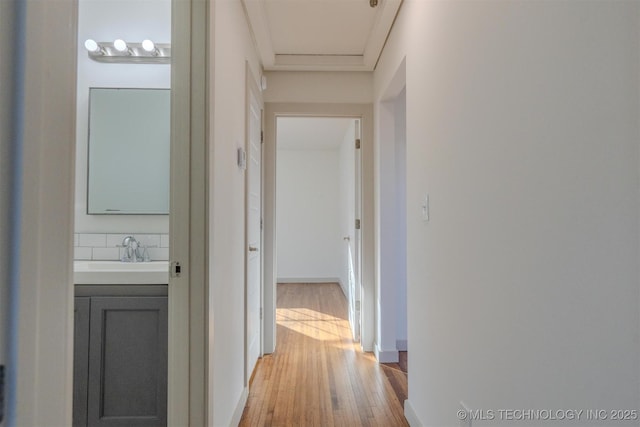 hall with crown molding, wood-type flooring, and sink