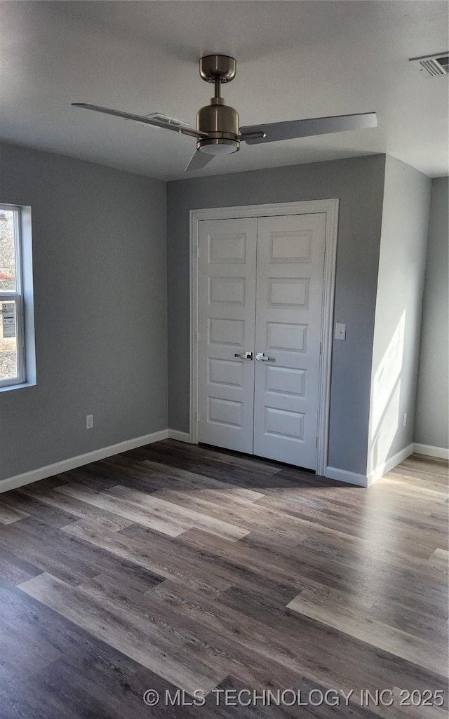 unfurnished bedroom with ceiling fan, wood-type flooring, and a closet