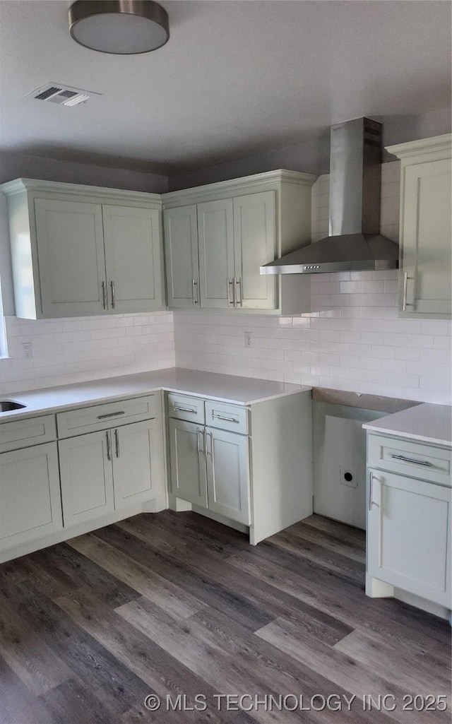 kitchen with tasteful backsplash, white cabinetry, wall chimney range hood, and dark hardwood / wood-style flooring