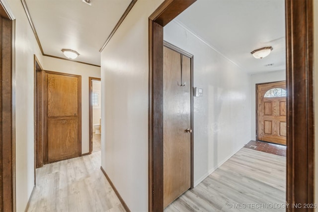 hallway featuring ornamental molding and light hardwood / wood-style flooring