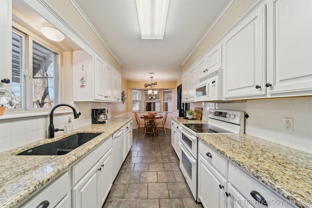 kitchen with sink, white cabinetry, white appliances, light stone countertops, and decorative backsplash