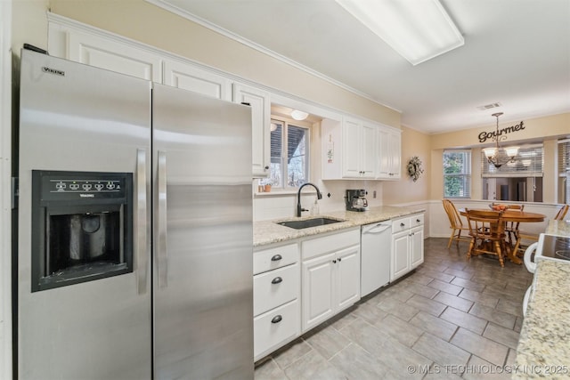 kitchen with sink, white cabinets, stainless steel fridge, hanging light fixtures, and white dishwasher