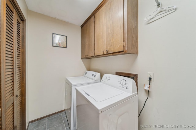 washroom with light tile patterned floors, washer and clothes dryer, and cabinets