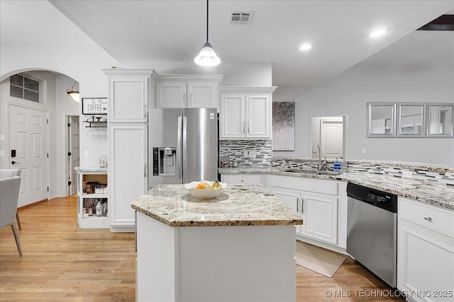 kitchen with sink, appliances with stainless steel finishes, white cabinets, a kitchen island, and decorative light fixtures