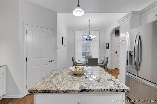 kitchen featuring white cabinets, a kitchen island, stainless steel fridge, and decorative light fixtures