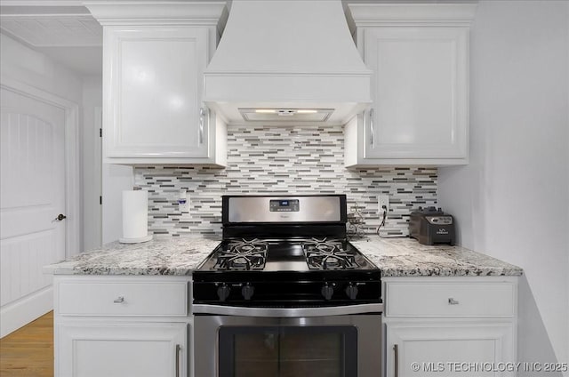 kitchen featuring white cabinetry, light stone counters, gas stove, and custom range hood