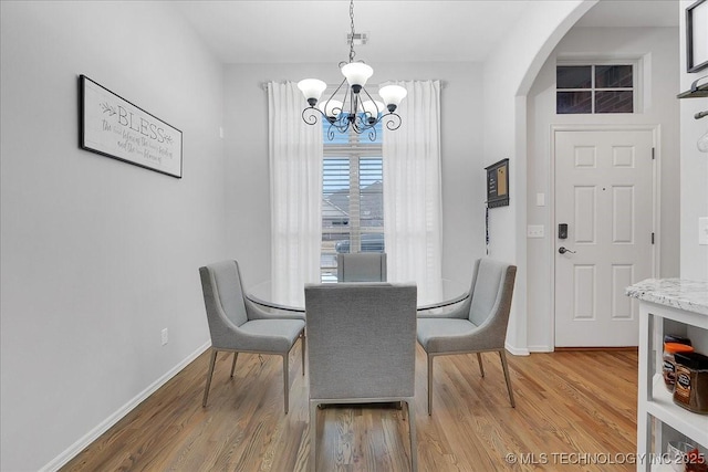 dining area with wood-type flooring and an inviting chandelier