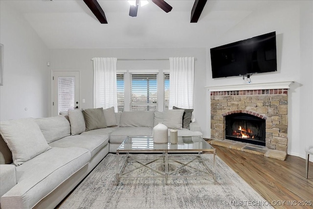 living room featuring wood-type flooring, vaulted ceiling with beams, ceiling fan, and a fireplace