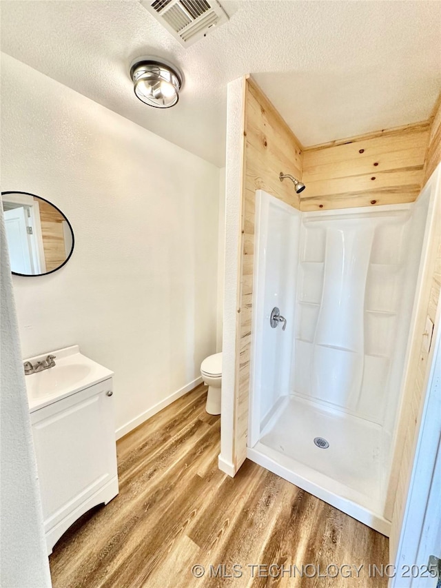 bathroom featuring hardwood / wood-style flooring, walk in shower, a textured ceiling, and toilet