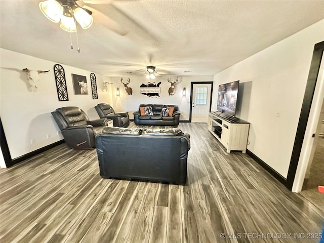 living room featuring ceiling fan, dark hardwood / wood-style flooring, and a textured ceiling