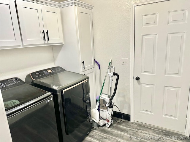 laundry room with cabinets, washer and dryer, and light hardwood / wood-style flooring