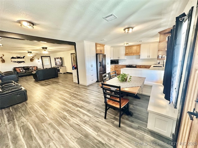 dining room featuring sink, light hardwood / wood-style floors, a textured ceiling, and ceiling fan