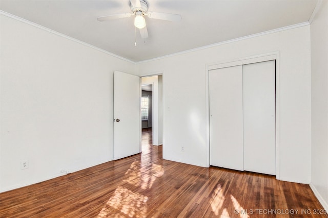 unfurnished bedroom featuring crown molding, dark wood-type flooring, a closet, and ceiling fan