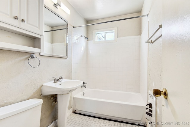 bathroom with tile patterned flooring, tiled shower / bath combo, and toilet