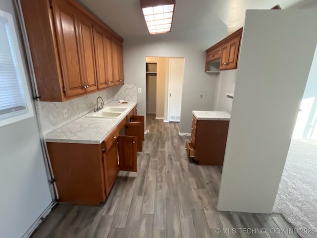 kitchen with sink, backsplash, and light wood-type flooring