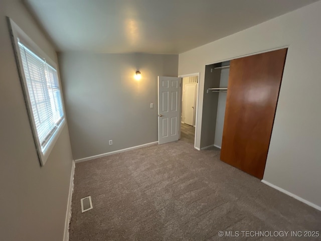 unfurnished bedroom featuring dark carpet and a closet