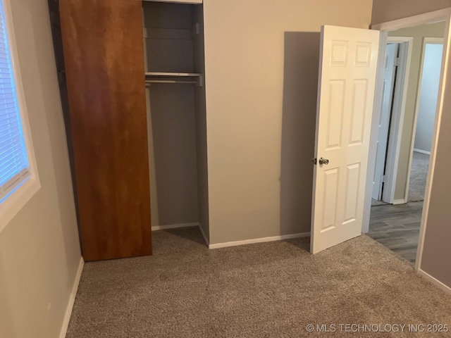 unfurnished bedroom with dark carpet and a closet