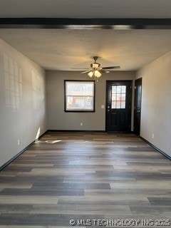 interior space featuring ceiling fan, dark wood-type flooring, and beamed ceiling