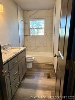 full bathroom featuring hardwood / wood-style flooring, tiled shower / bath, vanity, and toilet