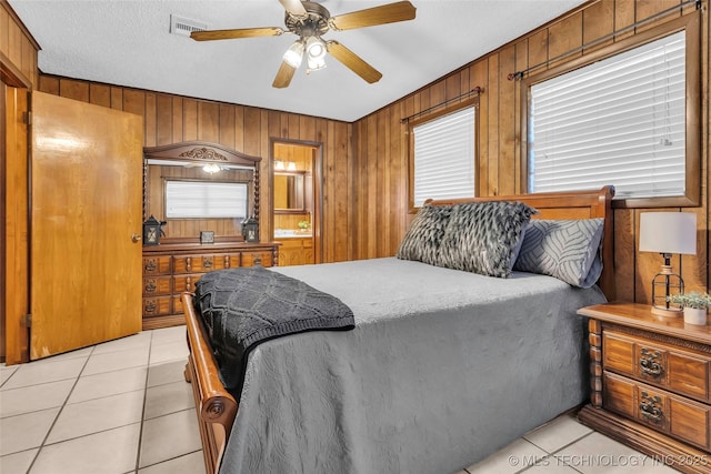 tiled bedroom featuring ceiling fan, a textured ceiling, and wooden walls