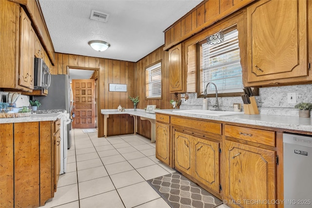 kitchen featuring sink, decorative backsplash, light tile patterned floors, white appliances, and a textured ceiling