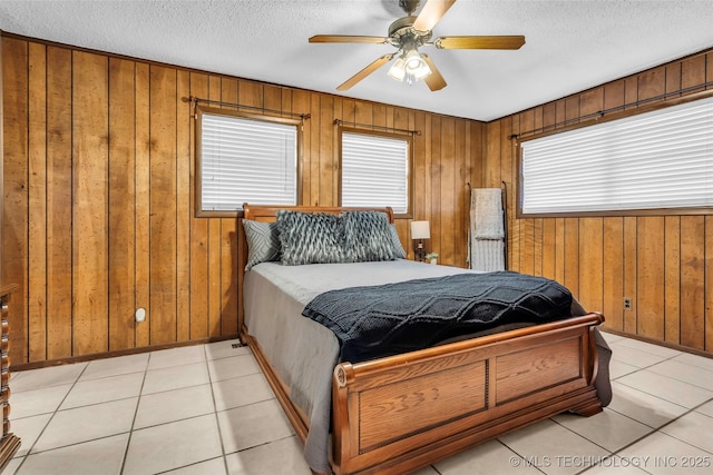 tiled bedroom featuring ceiling fan, a textured ceiling, and wood walls