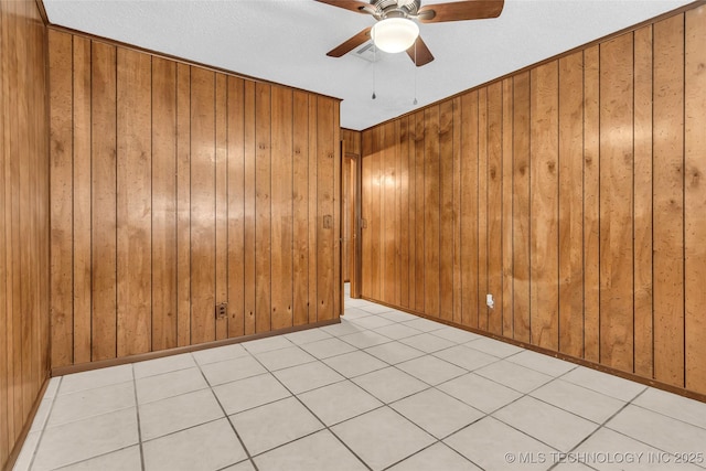 empty room featuring ceiling fan and wood walls