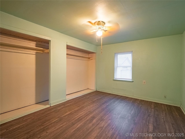 unfurnished bedroom featuring dark hardwood / wood-style flooring and two closets