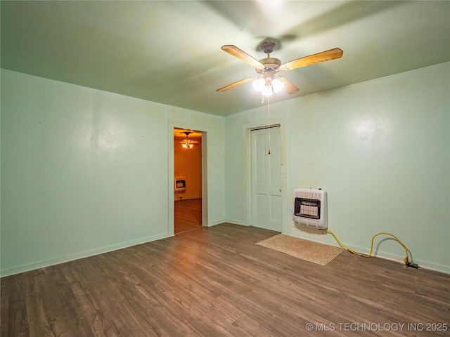 empty room featuring ceiling fan, dark hardwood / wood-style floors, heating unit, and a wood stove