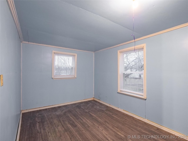 empty room featuring ornamental molding and dark wood-type flooring