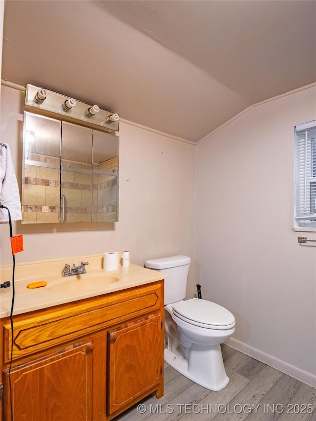 bathroom featuring vaulted ceiling, hardwood / wood-style floors, vanity, and toilet