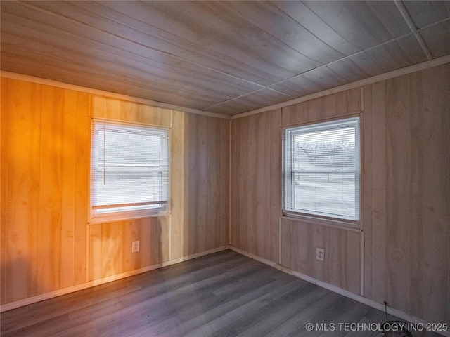 spare room featuring a healthy amount of sunlight, dark hardwood / wood-style floors, and wood walls