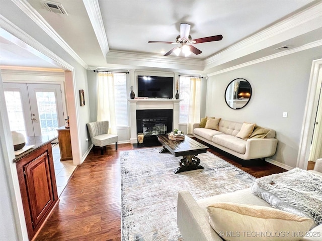 living room with crown molding, dark wood-type flooring, and a tray ceiling