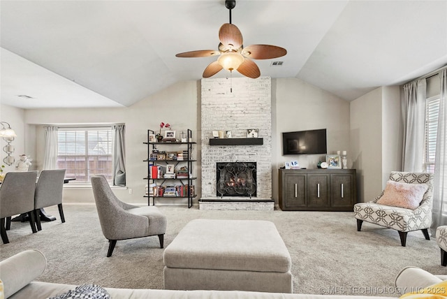 living room with ceiling fan, lofted ceiling, a fireplace, and light carpet