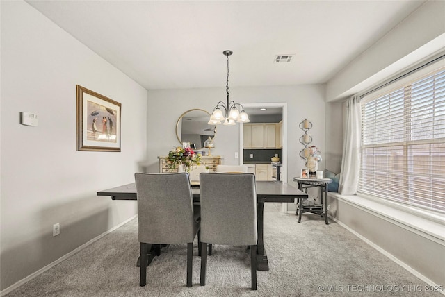 carpeted dining area with an inviting chandelier