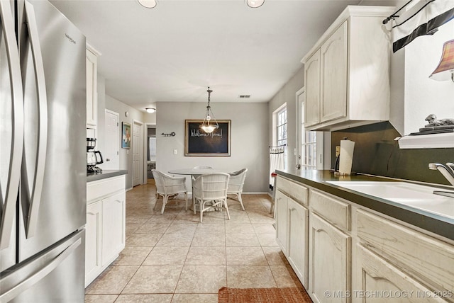 kitchen featuring stainless steel fridge, sink, hanging light fixtures, and light tile patterned floors