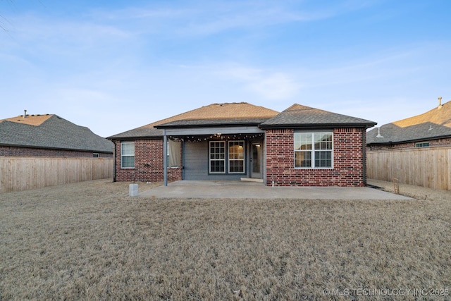 back of property with a yard and a patio area